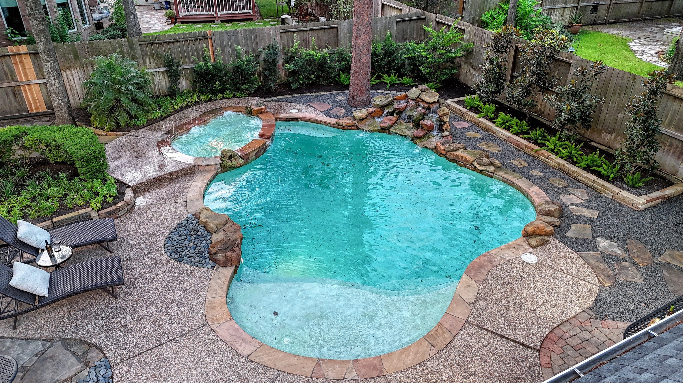 911 Chisel Point Drive Houston, TX 77094 - Photo 48 of 50 Overhead view of the private backyard, highlighting the organic pool design with beach entry, spa, and rock waterfall, complemented by multiple seating areas and vibrant greenery.