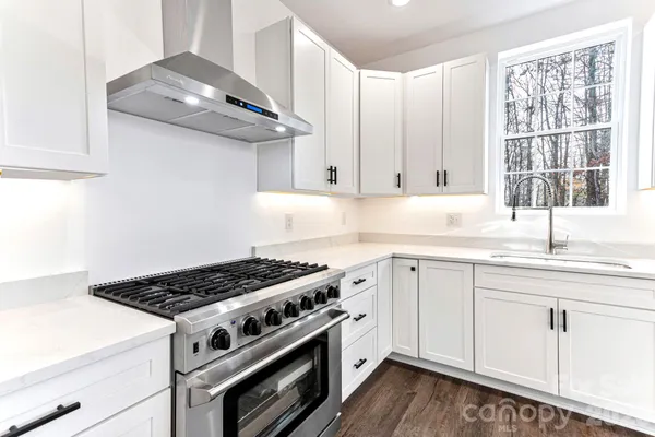 a kitchen with stainless steel appliances a stove a sink and white cabinets