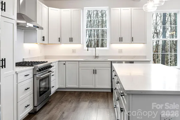 a kitchen with a sink appliances cabinets and a large window