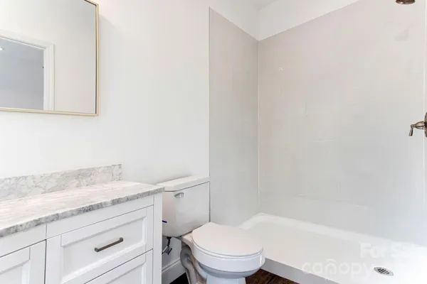 a bathroom with a granite countertop toilet sink and mirror