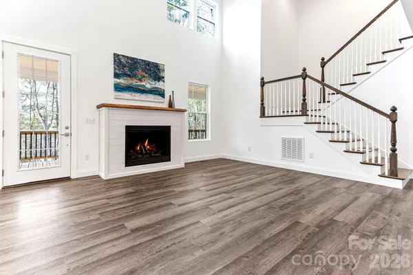 a view of an empty room with wooden floor and fireplace