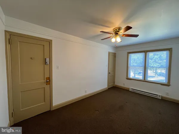 an empty room with a window and a fan