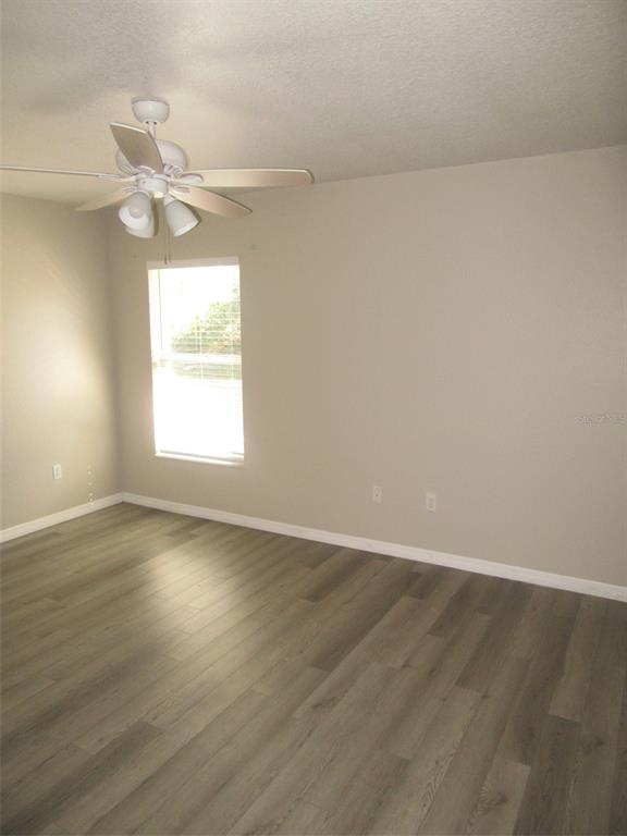 1090 Nomad Road Punta Gorda, FL 33983 - Photo 11 of 16 an empty room with wooden floor fan and windows