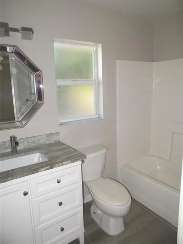 a bathroom with a granite countertop toilet sink and mirror