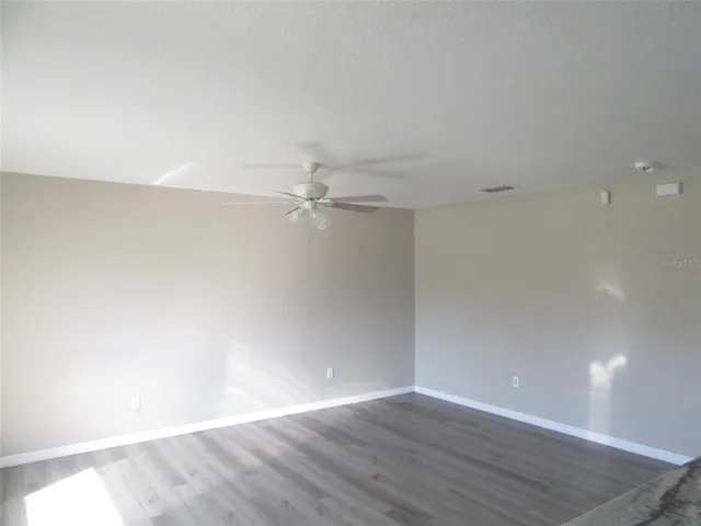 an empty room with wooden floor and fan