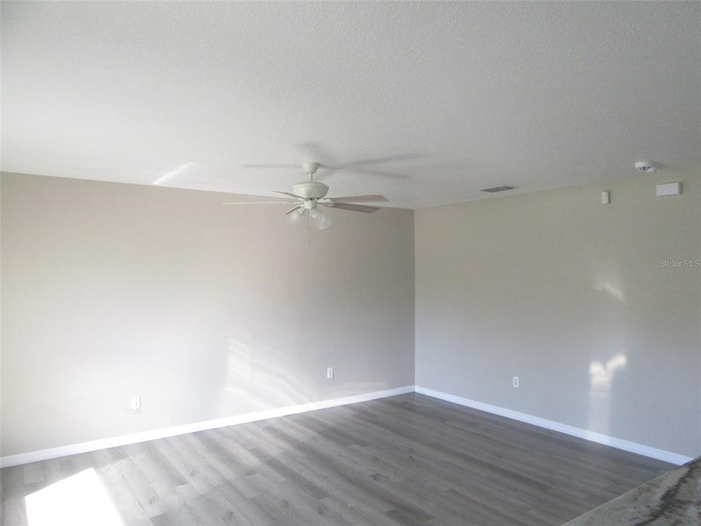 1090 Nomad Road Punta Gorda, FL 33983 - Photo 3 of 16 an empty room with wooden floor and fan