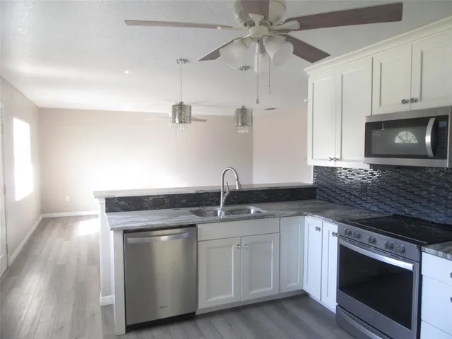 a kitchen with white cabinets stainless steel appliances and a sink