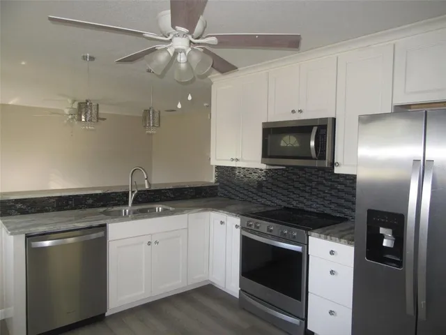 a kitchen with granite countertop a sink stainless steel appliances and white cabinets