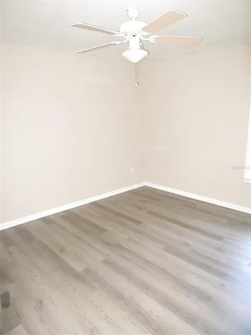 an empty room with wooden floor and fan