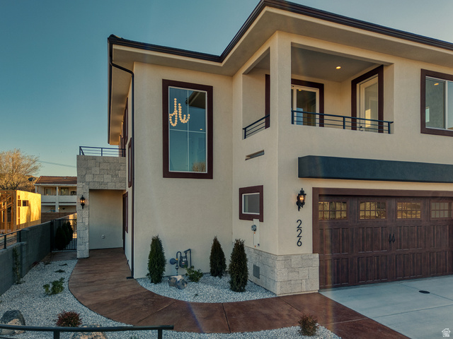 226 East 1100 North Hurricane, UT 84737 - Photo 1 of 49 View of front of home with stone siding, stucco siding, an attached garage, a balcony, and concrete driveway