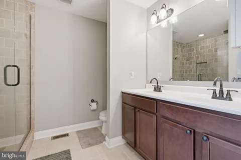 a spacious bathroom with a double vanity sink a mirror and a shower