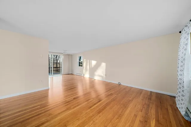 a view of empty room with wooden floor and window