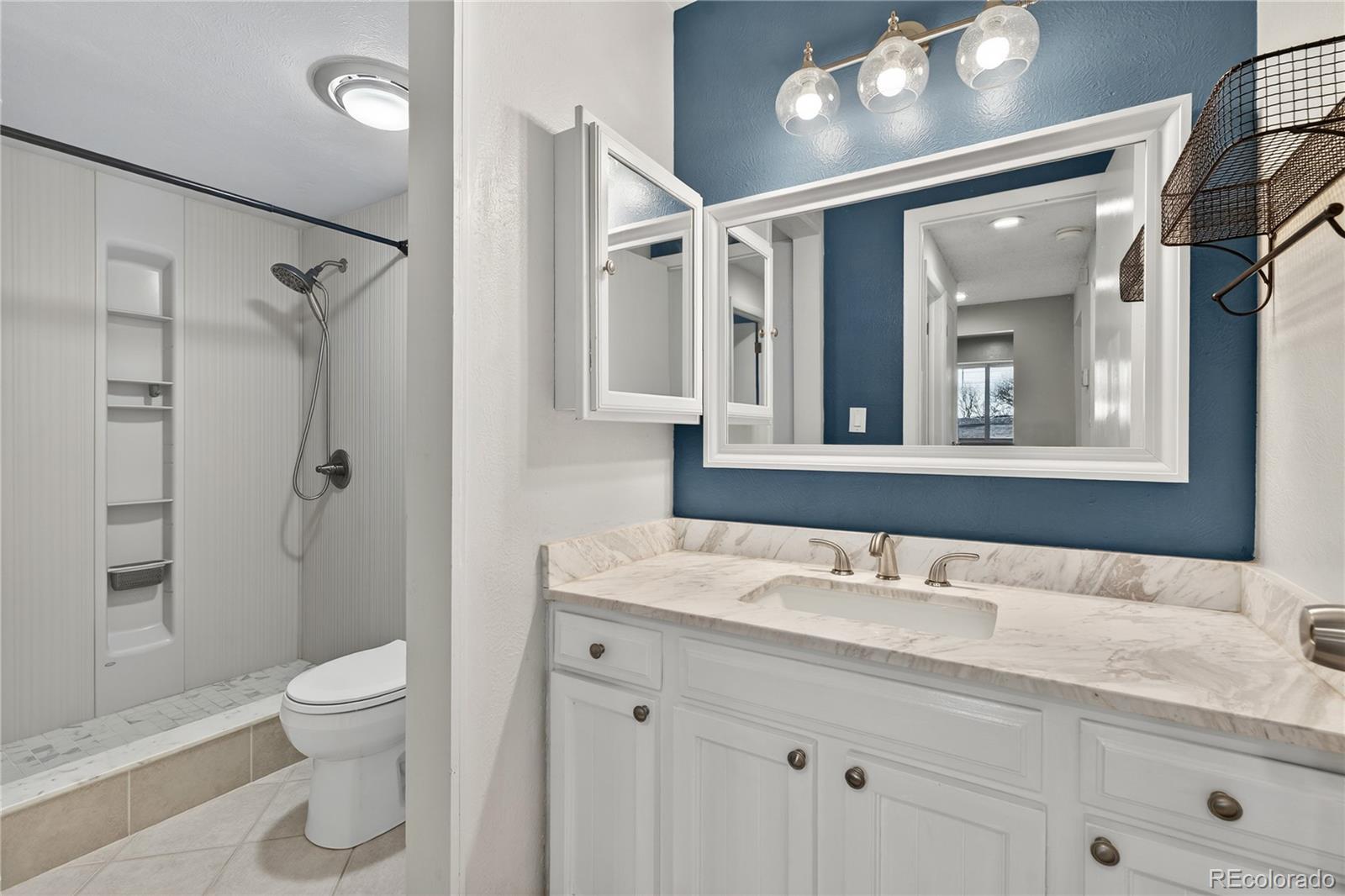 4066 South Atchison Way, Unit 101 Aurora, CO 80014 - Photo 16 of 36 a bathroom with a granite countertop sink toilet a large mirror a shower and vanity