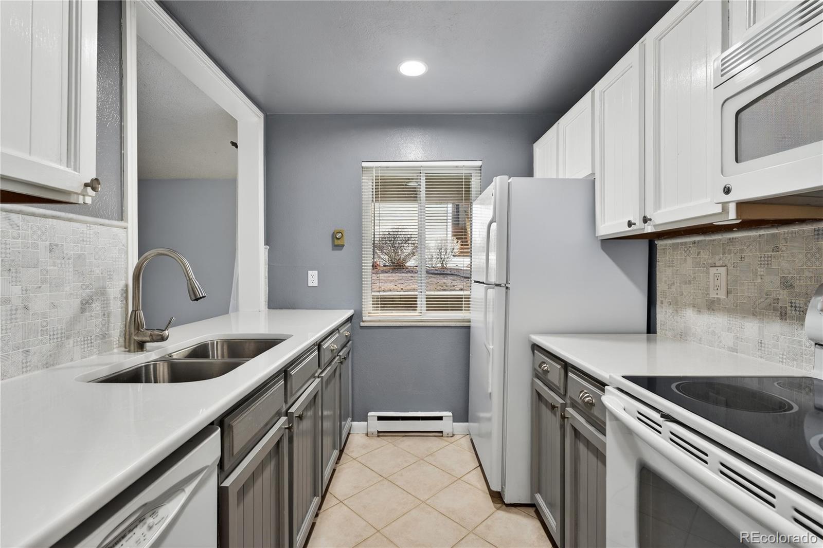 4066 South Atchison Way, Unit 101 Aurora, CO 80014 - Photo 6 of 36 a kitchen that has a sink a stove and cabinets