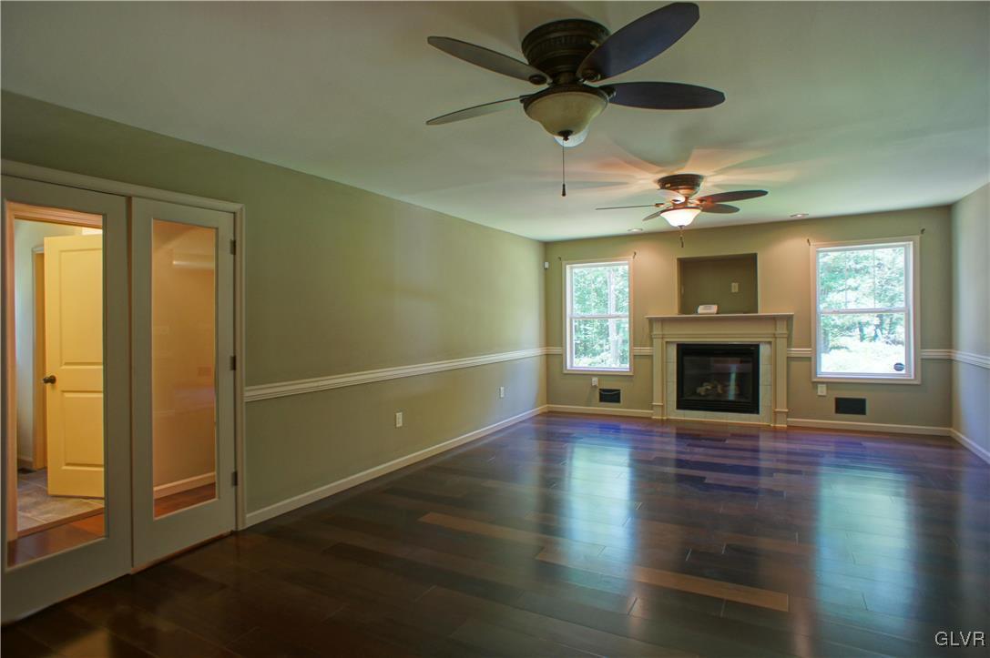 600 Henry's Crossing Road Cresco, PA 18326 - Photo 17 of 39 an empty room with wooden floor a ceiling fan a fireplace and windows
