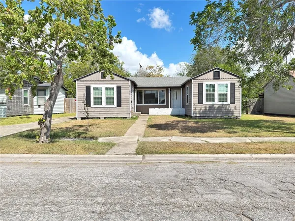 a front view of a house with a yard and trees