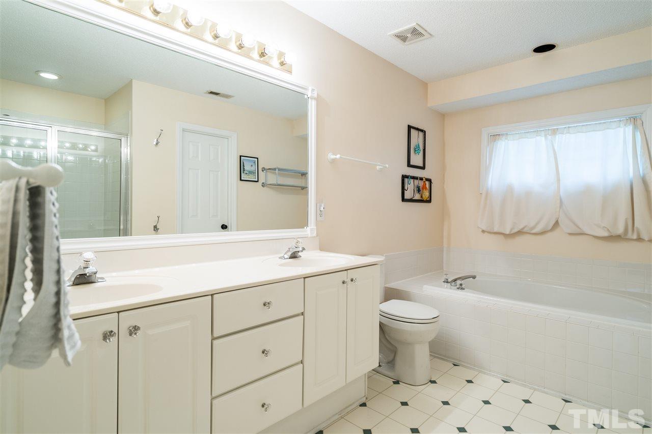 3316 Stone Castle Court Raleigh, NC 27613 - Photo 18 of 25 a bathroom with a sink a toilet a large mirror and shower