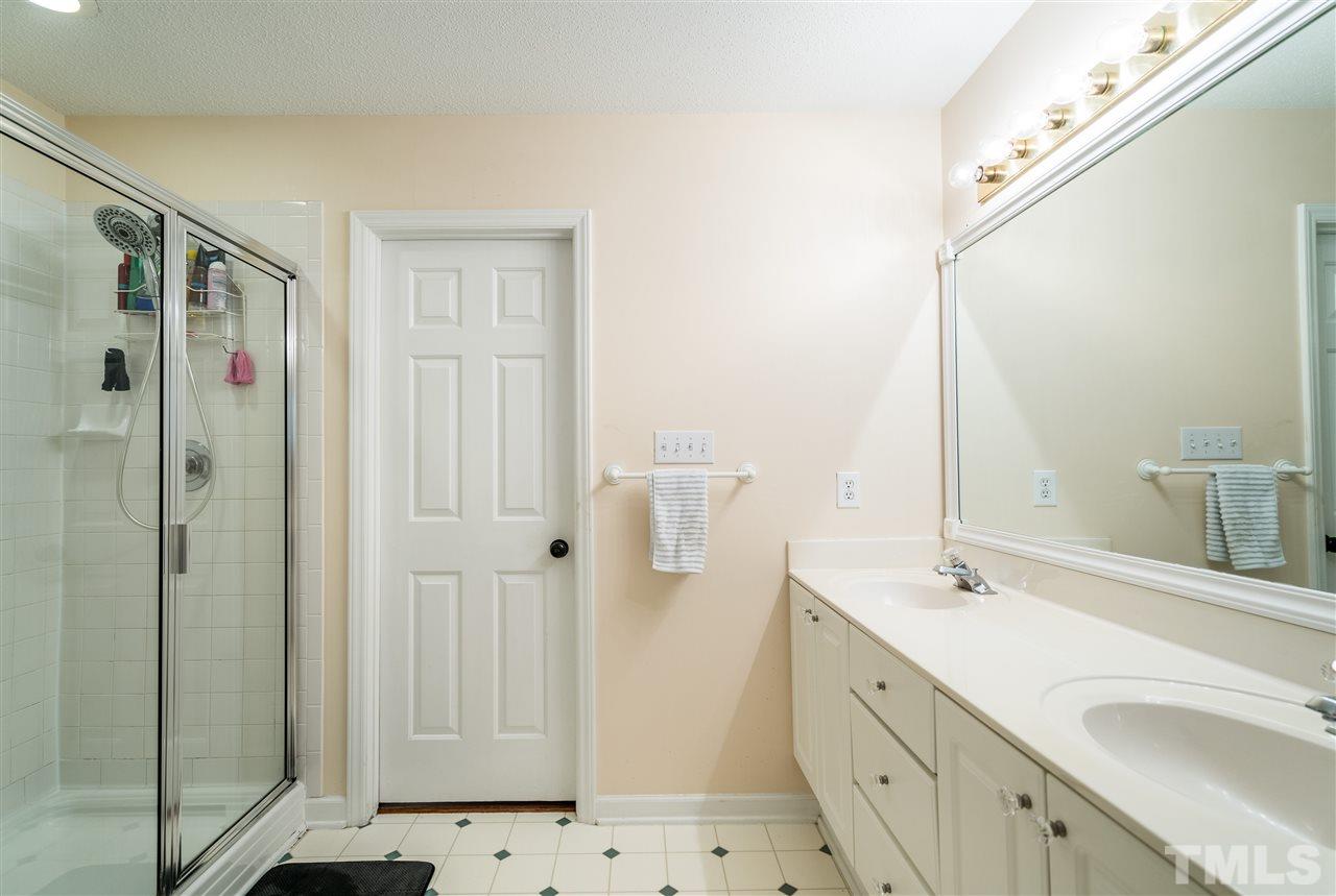 3316 Stone Castle Court Raleigh, NC 27613 - Photo 19 of 25 a bathroom with a double vanity sink a mirror and shower