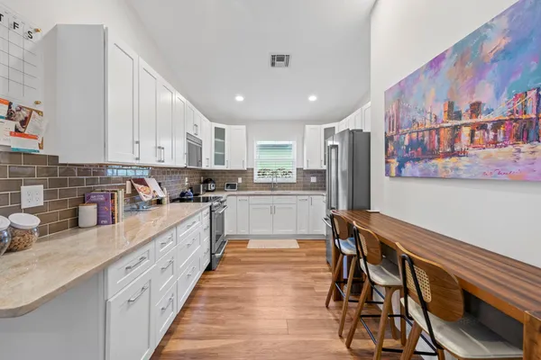 a large kitchen with stainless steel appliances granite countertop a refrigerator and a stove top oven