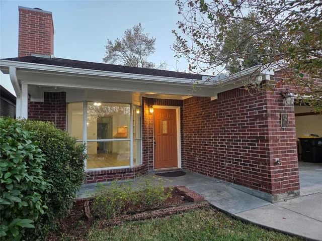 a view of brick house with large windows and a large tree