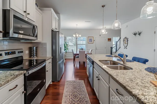 a kitchen with granite countertop stainless steel appliances a sink a stove top oven a counter space and cabinets