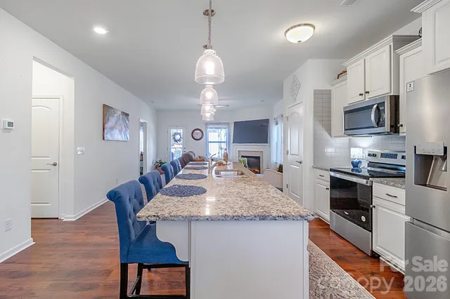 a kitchen with stainless steel appliances granite countertop a kitchen island hardwood floor sink stove dining table and chairs