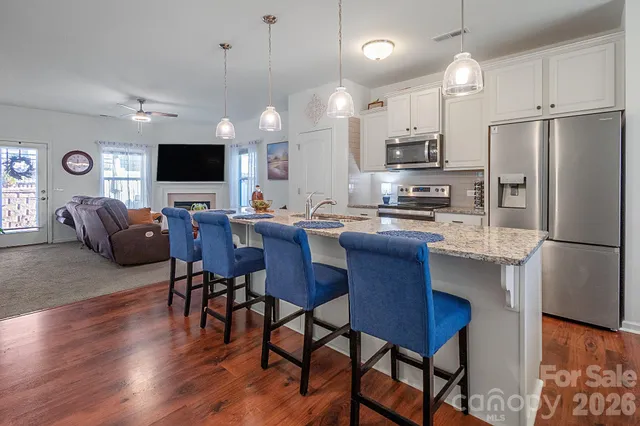 a kitchen with stainless steel appliances a dining table chairs refrigerator and microwave