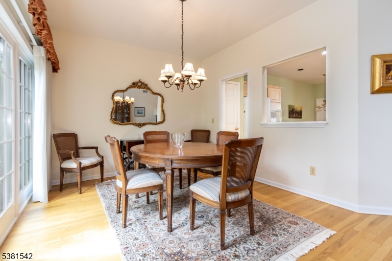 12 Hurlingham Club Road Far Hills, NJ 07931 - Photo 14 of 31 a dining room with wooden floor a chandelier a wooden table and chairs