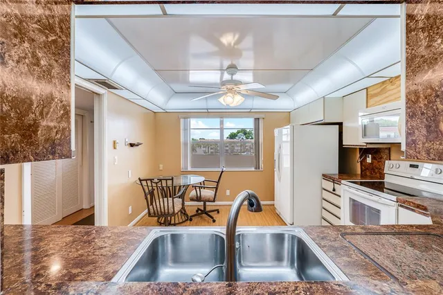 a kitchen that has a cabinets a sink a stove and a dining table with chandelier