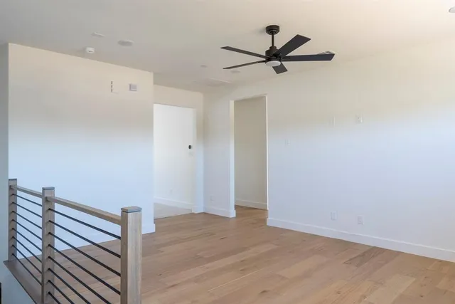 a view of room with wooden floor and a ceiling fan