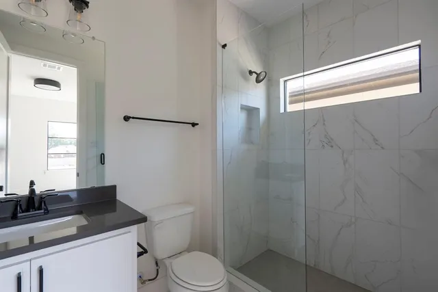 a bathroom with a granite countertop sink toilet and shower