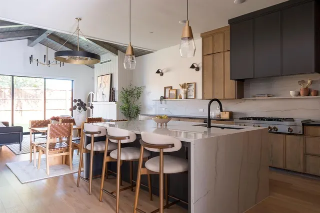 a kitchen with stainless steel appliances granite countertop a stove top oven a sink a dining table and chairs with wooden floor