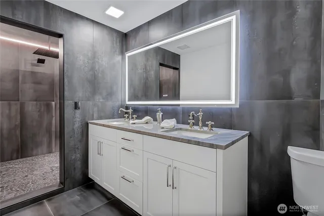 a bathroom with a double vanity sink a toilet and a mirror