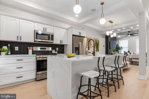 a kitchen with stainless steel appliances a refrigerator a stove a dining table and chairs with wooden floor