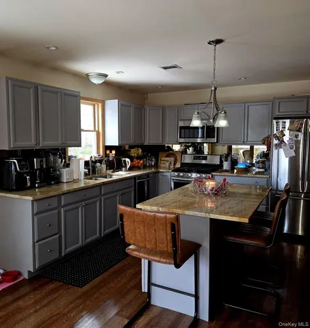 a kitchen with stainless steel appliances kitchen island granite countertop a sink a stove a refrigerator cabinets and chairs