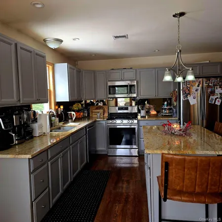 a kitchen with kitchen island granite countertop a sink cabinets and stainless steel appliances