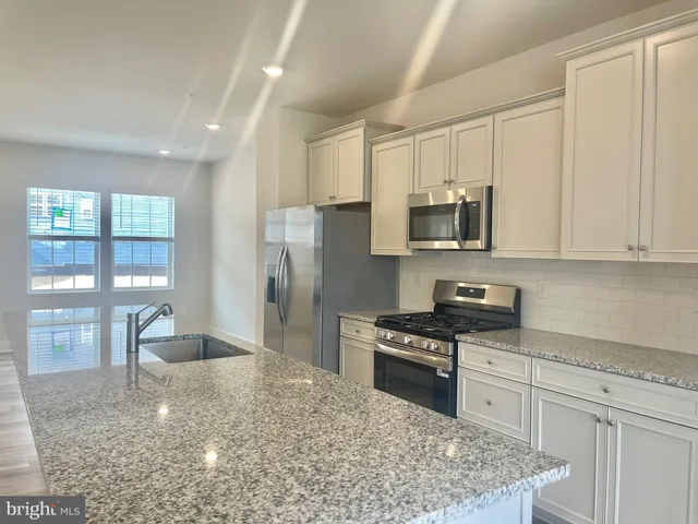 a kitchen with granite countertop a stove a sink and a refrigerator