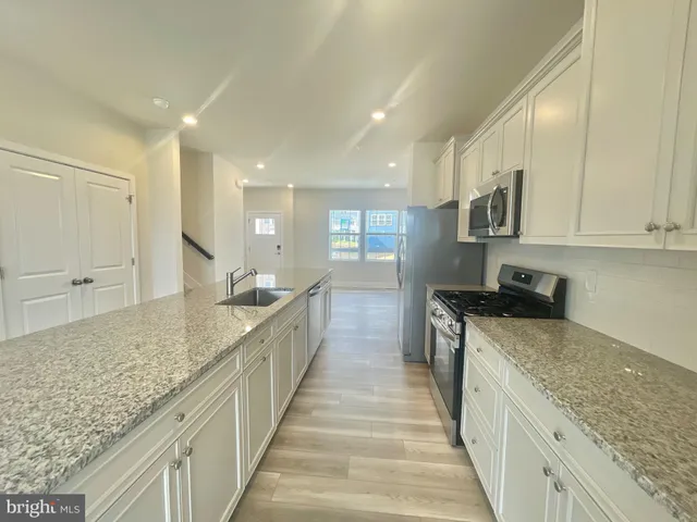 a large kitchen with stainless steel appliances granite countertop a lot of counter space and wooden floor