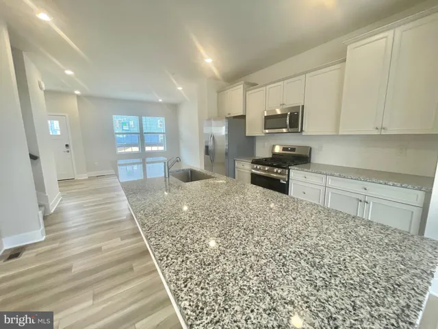 a kitchen with stainless steel appliances granite countertop a stove a sink and a refrigerator