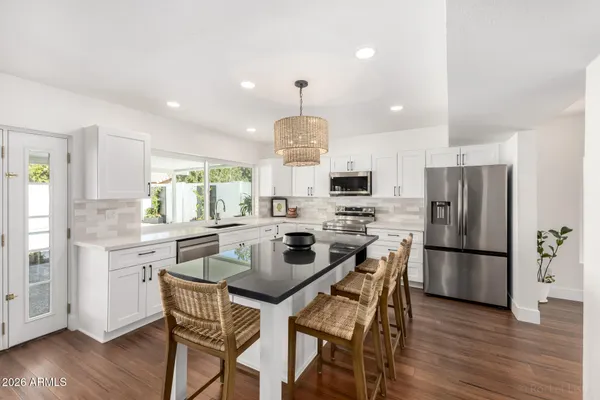 a kitchen with a dining table cabinets appliances and wooden floor