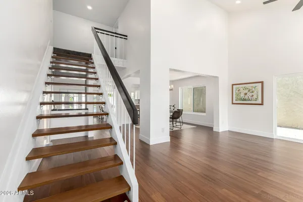 an empty room with wooden floor chandelier and windows