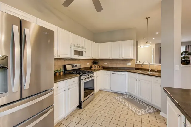 a kitchen with stainless steel appliances granite countertop a refrigerator a stove and a sink