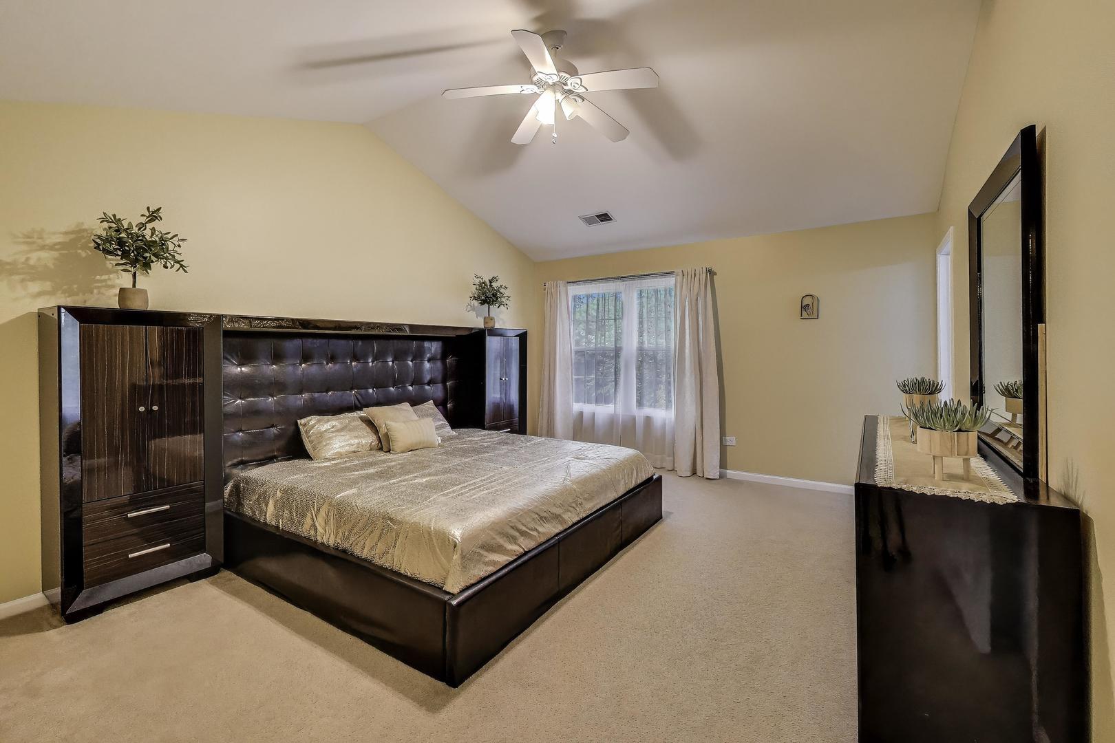 24115 Pear Tree Circle Plainfield, IL 60585 - Photo 8 of 15 a bedroom with a large bed and a chandelier