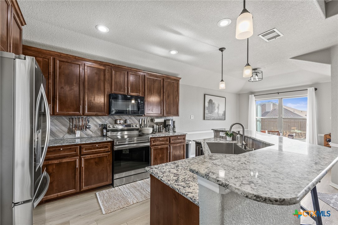 3437 Samuel Street Copperas Cove, TX 76522 - Photo 9 of 31 a kitchen with stainless steel appliances granite countertop sink stove refrigerator and cabinets