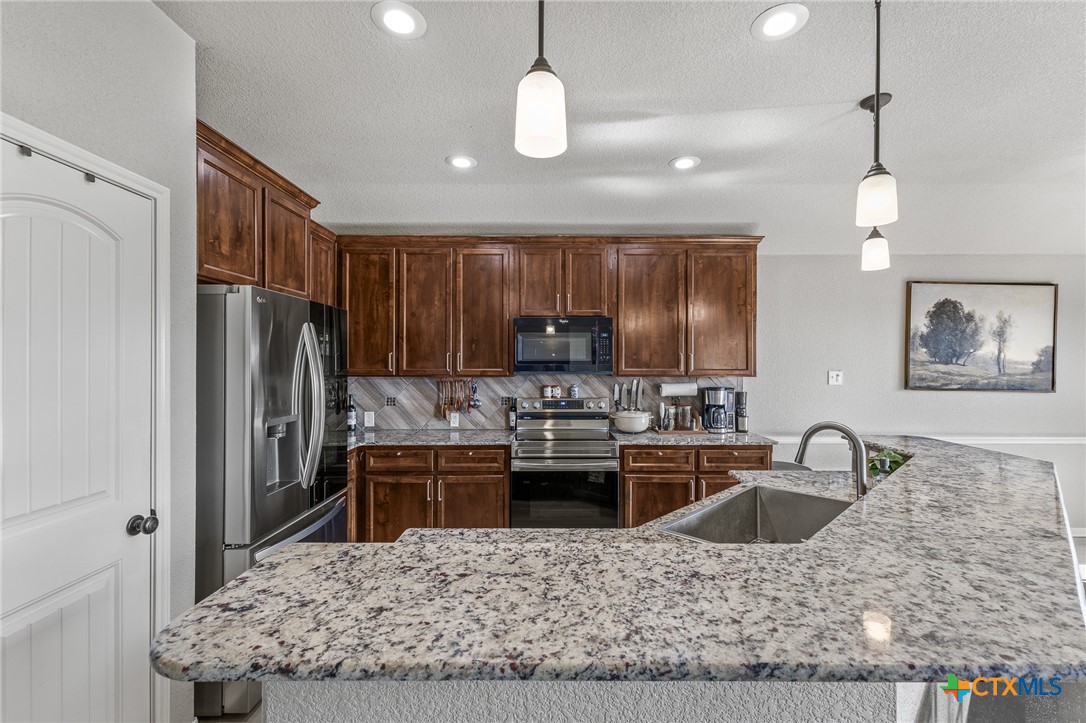 3437 Samuel Street Copperas Cove, TX 76522 - Photo 10 of 31 a kitchen with kitchen island granite countertop a sink stove and refrigerator