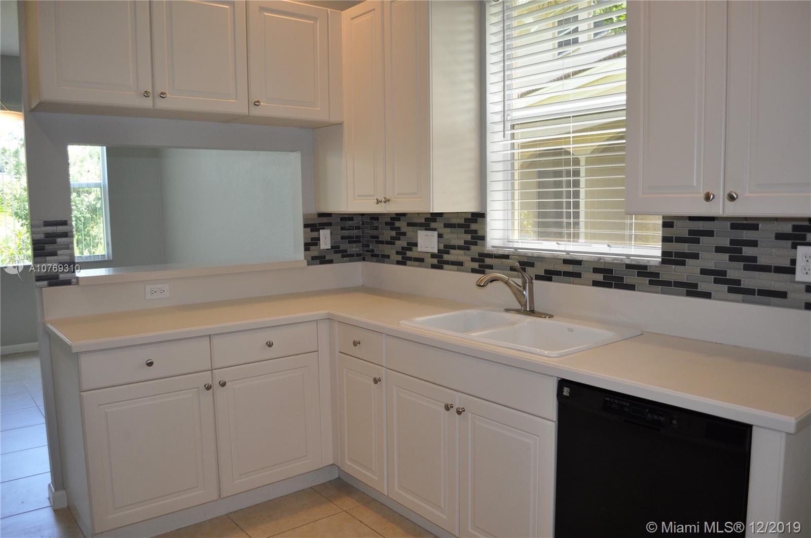 332 Southwest Otter Run Place, Unit 332 Stuart, FL 34997 - Photo 8 of 24 Extra windows, white cabinets, granite countertops and a pretty backsplash make this a delightful kitchen.