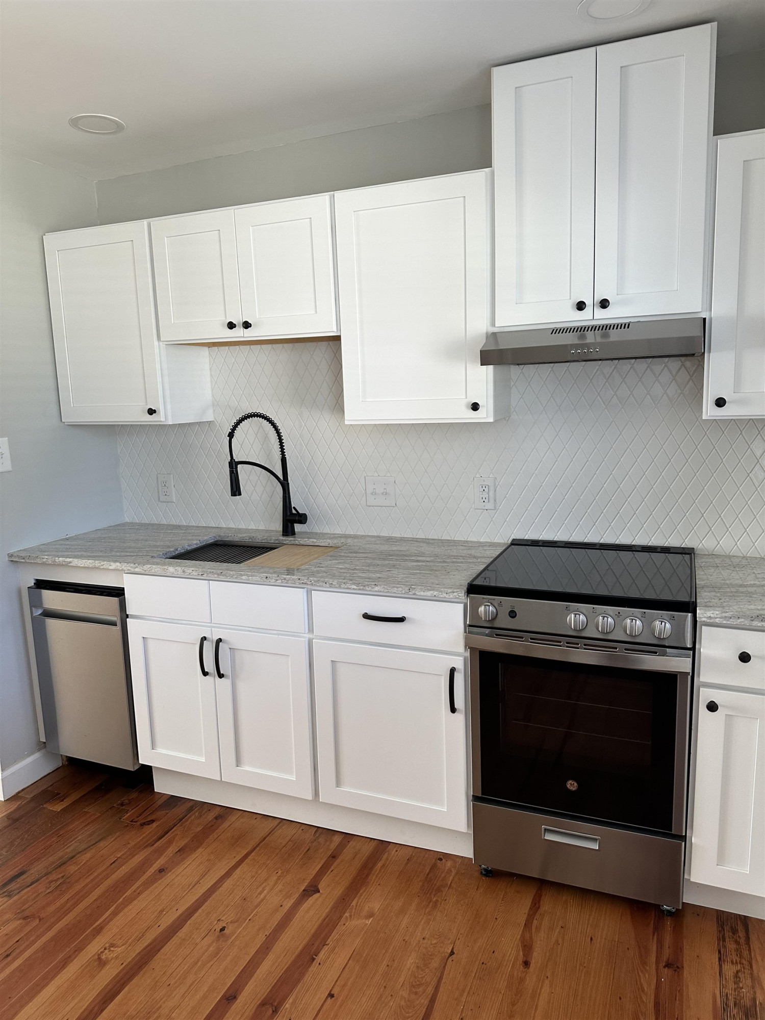 2344 Bernard Street, Unit 3 Raleigh, NC 27608 - Photo 5 of 15 a kitchen with granite countertop a stove a sink and a white cabinets with wooden floor