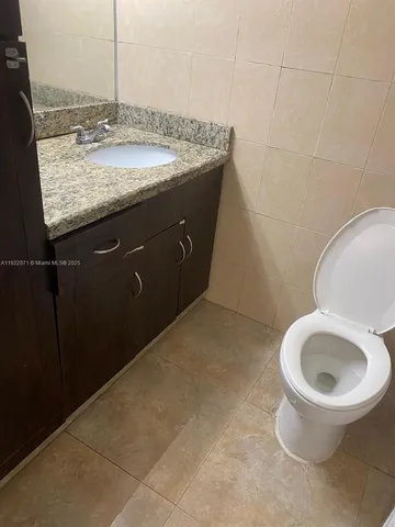 a bathroom with a granite countertop sink and a toilet