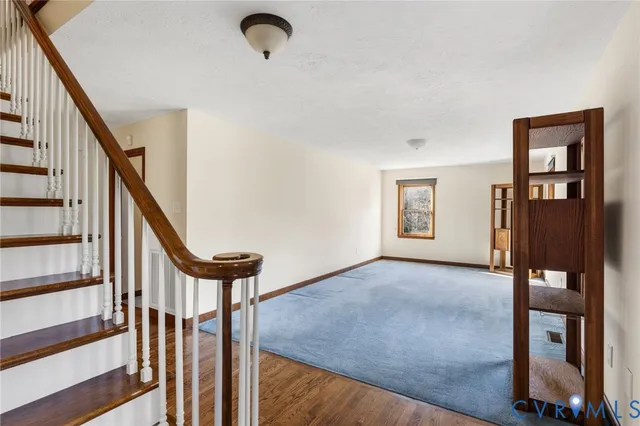 a view of an empty room with stairs and a window