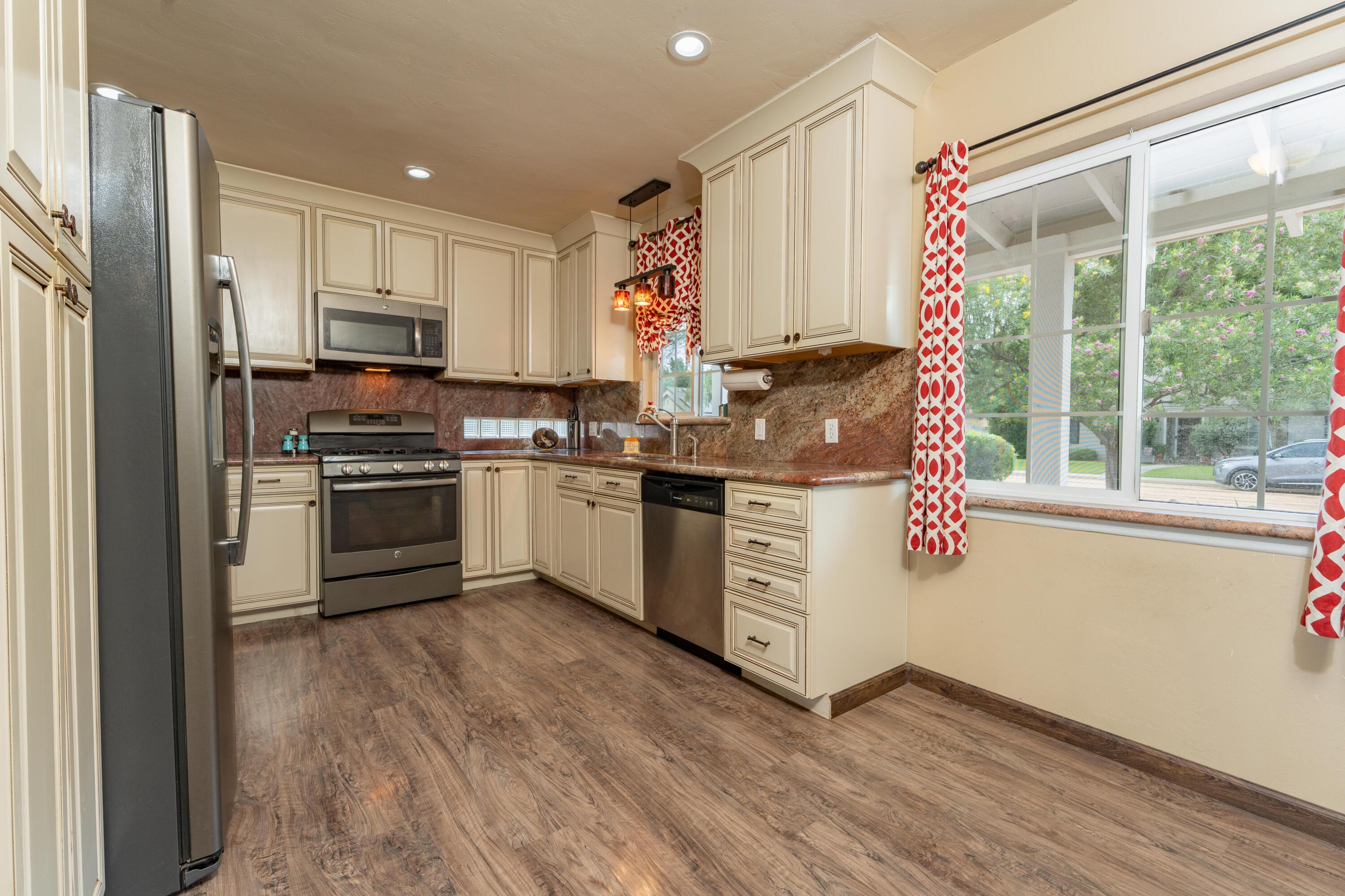 570 North Birch Avenue Reedley, CA 93654 - Photo 14 of 52 a kitchen with stainless steel appliances a stove a sink dishwasher a refrigerator white cabinets and wooden floor